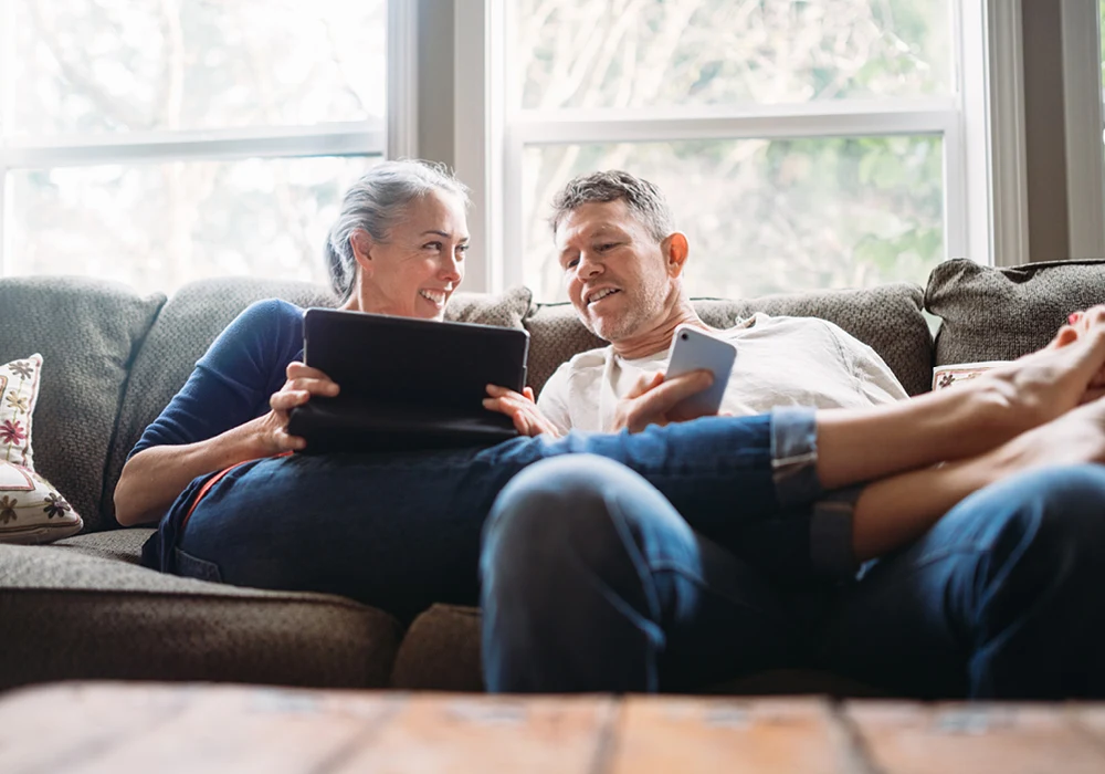 Two people on a sofa looking at mobile devices