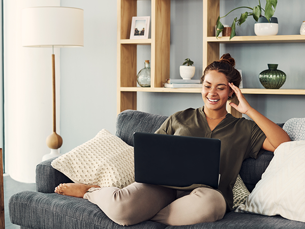 Young woman sitting on couch looking at laptop